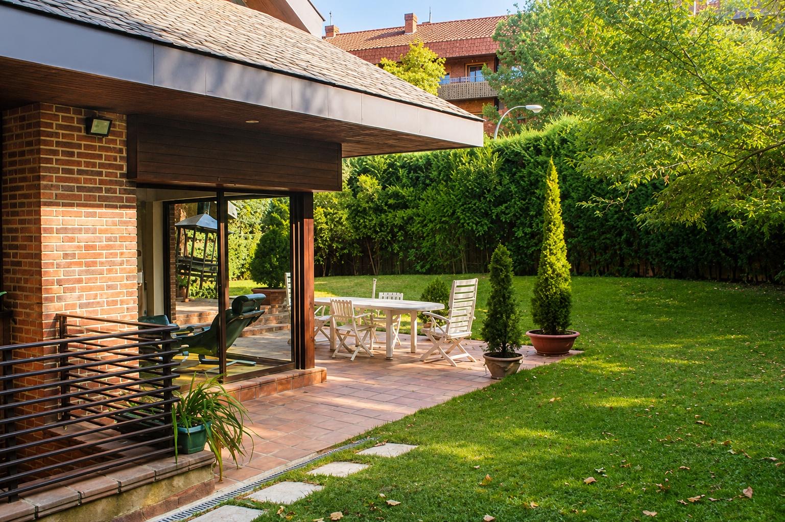 Jardín privado de chalet pareado en el Soto de la Moraleja con porche y zonas de descanso.